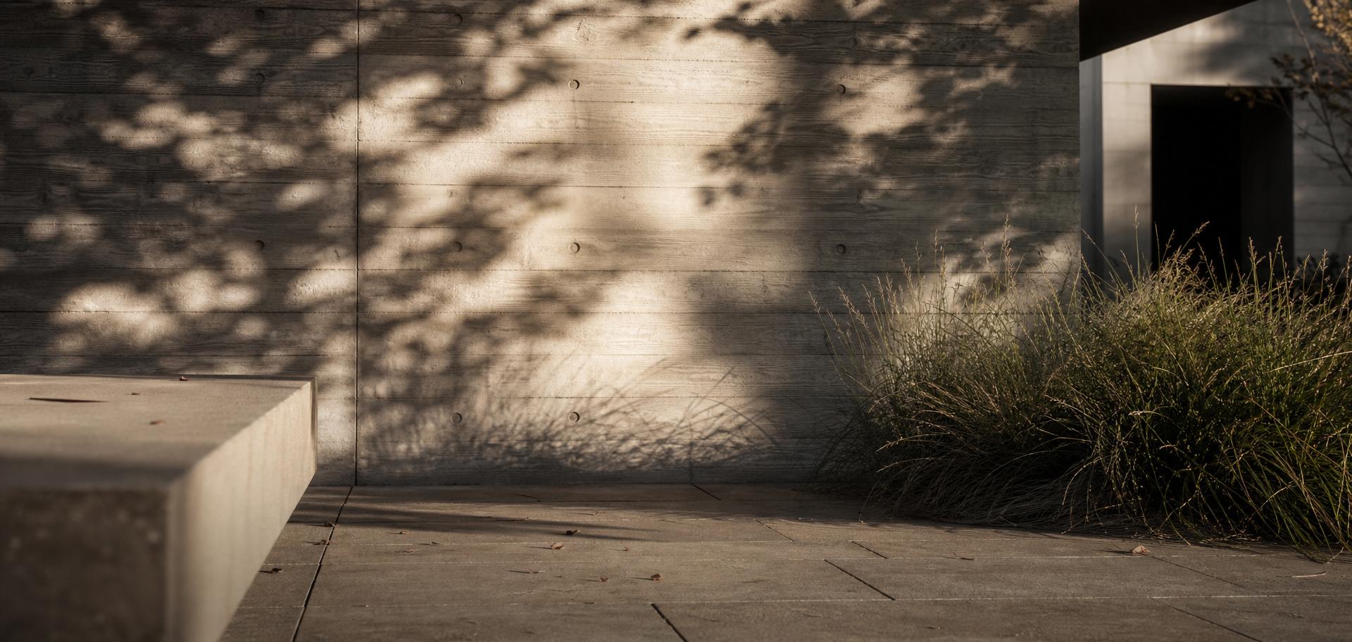 Board-formed concrete wall meeting sandstone terrace and native grasses